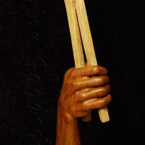 woodcarving of a hand holding tongs holding a horseshoe