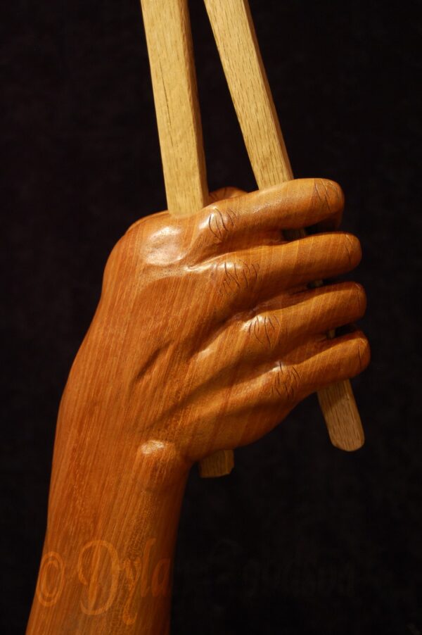 woodcarving of a hand holding tongs holding a horseshoe