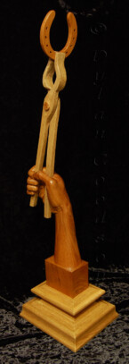wood sculpture of a hand holding a horseshoe with a pair of blacksmith's tong
