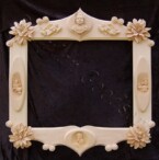 ornate frame incorporating large flowers, scrolls, angels relief carvings of little girls