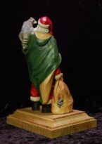 Santa Claus with a raccoon on his shoulder holding a walking stick carved by dylan goodson back view
