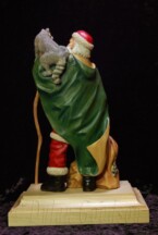 Santa Claus with a raccoon on his shoulder holding a walking stick carved by dylan goodson back view
