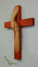 cross with the hand of Jesus grasping another hand carved by Dylan Goodson
