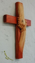 cross with the hand of Jesus grasping another hand carved by Dylan Goodson