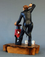 Dylan Goodson's wood carving of a magician standing on stage with wand upraised, about to conjure something out of the hat sitting on the table in front of him.