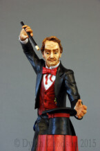 Standing with arm and wand up raised, the Magician stares into his empty hat sitting before him.